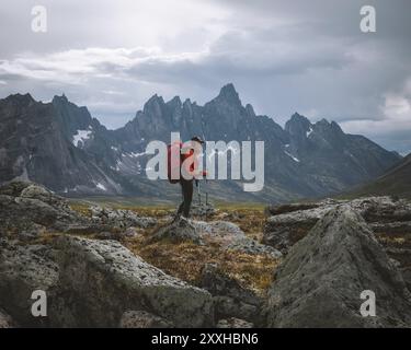 Hiker with backpack and trekking poles in a rugged mountainous landscape under a cloudy sky, A woman in Tombstone Territorial Park in the Yukon, Canad Stock Photo