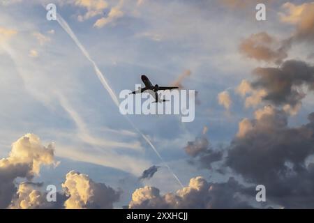 Clouds in the sky, silhouette of an aeroplane taking off. Dramatic clouds shortly in front of sunrise. Zurich, Switzerland, Europe Stock Photo