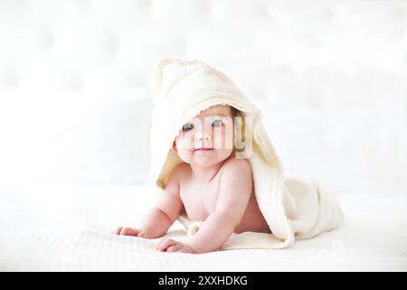 Six month baby wearing towel after bath. Childhood and baby care concept Stock Photo