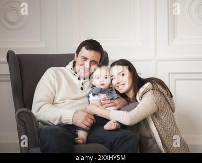 Happy smiling family with one year old baby girl indoor Stock Photo