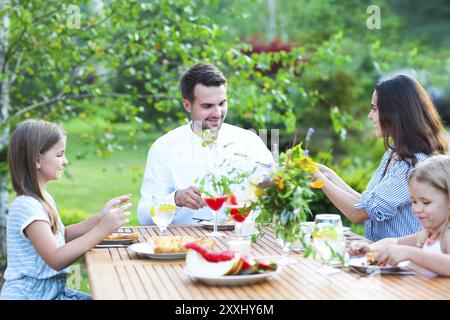 Happy family in the garden while having lunch in the evening Stock Photo