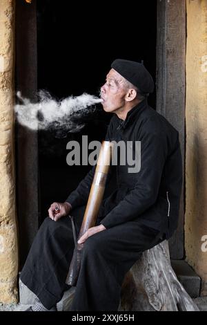 Ethnic minority Tay man smoking a pipe in Quan Ba, Ha Giang Province Vietnam Stock Photo