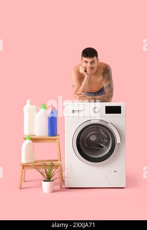 Young man doing laundry on pink background Stock Photo