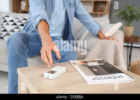 Young man taking air conditioner remote control from table at home, closeup Stock Photo