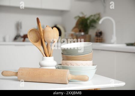 Wooden spoons with rolling pin and bowls on table in kitchen, closeup Stock Photo