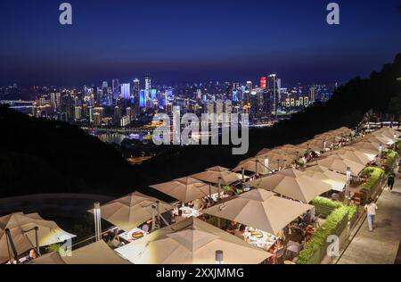 Chongqing, China. 23rd Aug, 2024. Tourists enjoy hotpot and the night view in a restaurant at the Nanshan scenic spot in Chongqing, southwest China, Aug. 23, 2024. Renowned tourist destinations in Chongqing, a city known for its high temperatures, attract many tourists in summer. Credit: Liu Chan/Xinhua/Alamy Live News Stock Photo