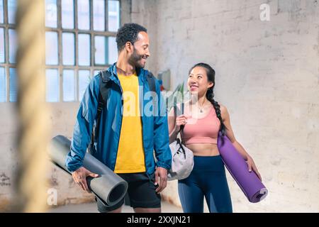 Cheerful male and female athlete standing together at gym. Smiling woman and male friends. Stock Photo