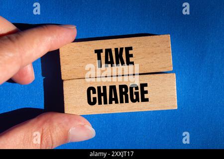 Take charge message written on wooden blocks on blue background. Conceptual take charge symbol. Copy space. Stock Photo