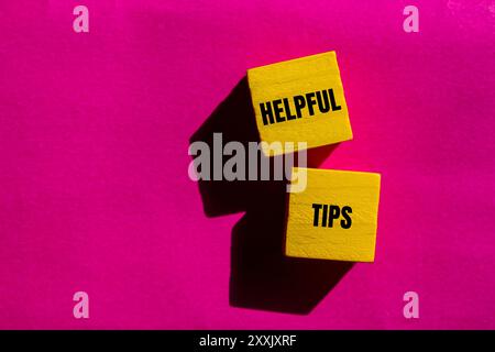 Helpful tips message written on yellow wooden cubes with pink background. Conceptual helpful tips symbol. Copy space. Stock Photo