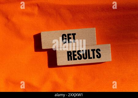 Get results message written on wooden blocks with orange background. Conceptual get results symbol. Copy space. Stock Photo