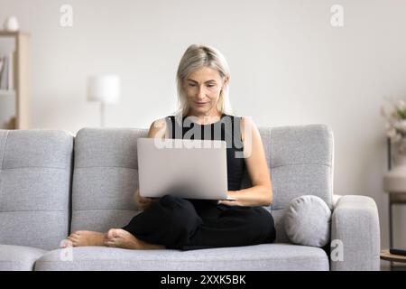 Mature woman working on laptop at home Stock Photo