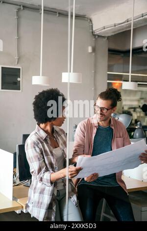 Diverse group of happy employees analyzing reports together with papers, working together in office Stock Photo