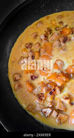 Fried eggs with mushrooms and yellow tomatoes in a frying pan. Home cooking. Vertical photo Stock Photo