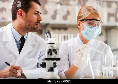 Researches in science laboratory. Low angle view of two young scientists making experiments while sitting in the laboratory Stock Photo