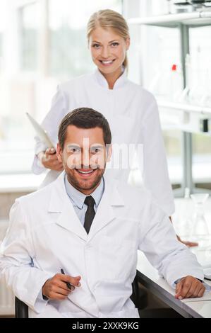 Medical experts. Two happy young scientists looking at camera and smiling while working together in the laboratory Stock Photo