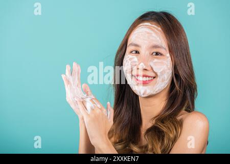 Portrait Asian young woman hands are adorned with white foam cleaning face studio shot isolated on Stock Photo