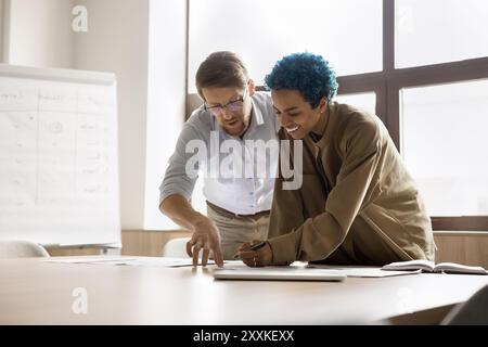Two colleagues standing at desk, examining printed documents Stock Photo
