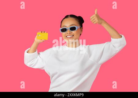 Young woman in sunglasses poses with a yellow card Stock Photo