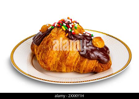Croissant garnished with chocolate and rainbow sprinkles. Closeup view single croissant garnished with chocolate and rainbow sprinkles in ceramic dish Stock Photo