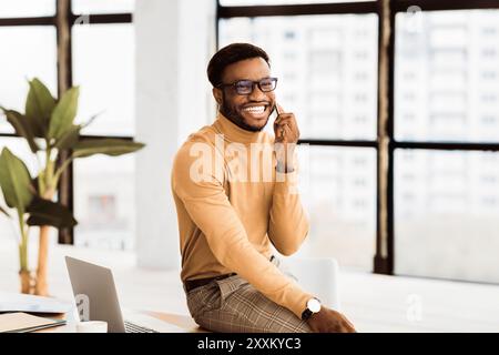 Black guy talking on phone sitting on the table Stock Photo