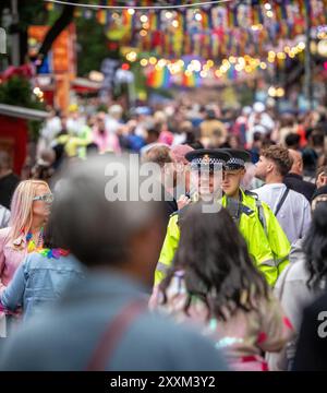 Manchester, UK. 25 Aug, 2024. Police officers walk down Canal street. Manchester Pride weekend have once again been told not to customise their uniforms with any emblems, badges or pride flags Chief Constable , Mr Stephen Watson,  gave an interview in 2021 which he said he believed the public was 'fed up' with 'virtue-signalling police officers' and believed that the impartiality of officers could be undermined by responses to campaign groups including actions such as taking the knee or wearing rainbow pins, badges or shoelaces.Manchester Pride 2024 . This year's theme is 'Buzzin To Be Queer - Stock Photo