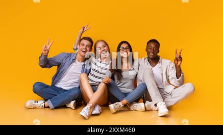 Happy students having fun over yellow studio background Stock Photo