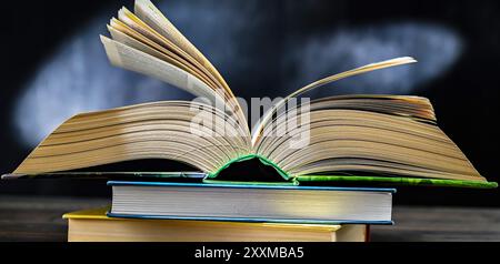 An open book lying on a stack of other books. Stock Photo