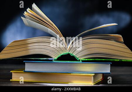 An open book lying on a stack of other books. Stock Photo