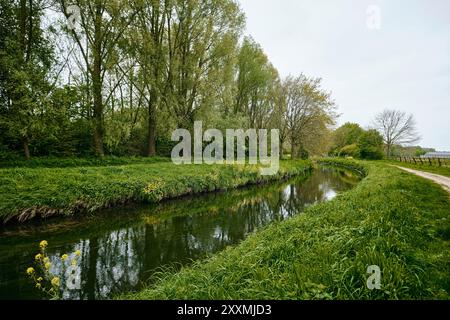 Limburg, Netherlands - April 10, 2024: Stream with its waters flowing   surrounded by green grass embankments in Sweikhuizen, Sittard - Geleen Stock Photo