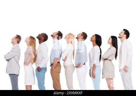What is that? Side view of positive diverse group of people in smart casual wear looking up while standing in a row and against white background Stock Photo