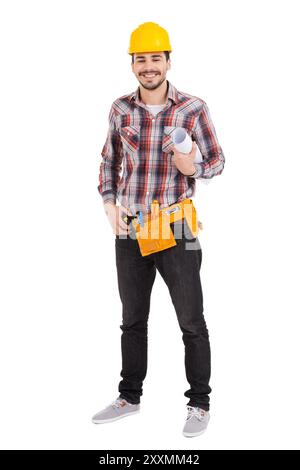 Confident repairman. Full length of confident young male carpenter in hardhat holding blueprint and smiling while standing against white background Stock Photo