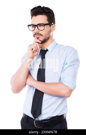 Waiting for inspiration. Thoughtful young man in shirt and tie looking away and touching his chin while standing against white background Stock Photo