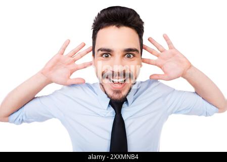 Excited businessman. Happy young man in shirt and tie looking at camera and touching his head with hands while standing against white background Stock Photo