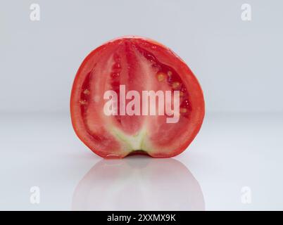 A juicy tomato sliced in half standing on a white background Stock Photo