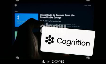 Person holding mobile phone with logo of American artificial intelligence company Cognition AI Inc. in front of web page. Focus on phone display. Stock Photo