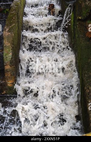 Water rushing through an old concrete drainage channel. Stock Photo