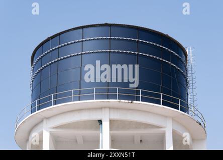 Large elevated industrial water tank against a clear blue sky. Stock Photo