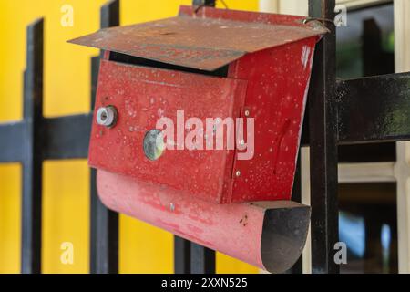 Vintage red mailbox on black fence with rustic charm. Stock Photo