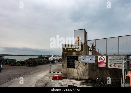 Fishing boats idle at Port Oriel, showcasing the calm waters and atmospheric clouds typical of County Louth on a quiet afternoon. Stock Photo