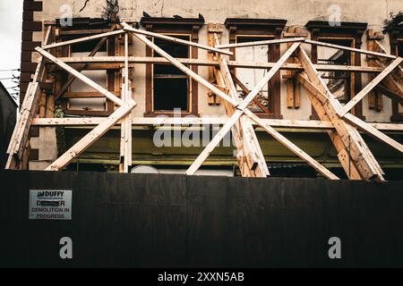 Workers are busy reinforcing a dilapidated structure with wooden beams during its demolition, In Narrow West Street, Drogheda, Co Louth, Ireland. Stock Photo