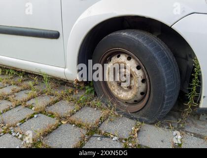 Rusty Car Wheel with Flat Tire on Pavement Stock Photo