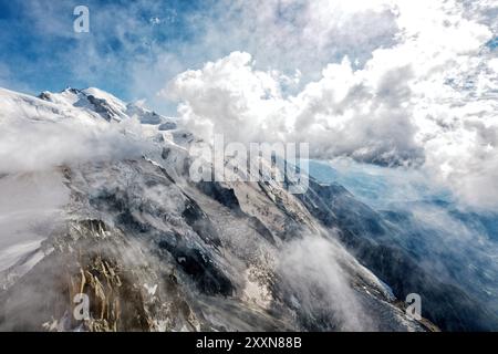 Dramatic Alpine landscape with snow‑covered peaks, steep rocky slopes and clouds drifting across the high mountain range. Stock Photo