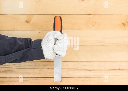 Working hand in glove holding a chisel with wall wood background Stock Photo