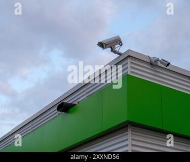 Surveillance cameras on the corner of an industrial building roof. Stock Photo