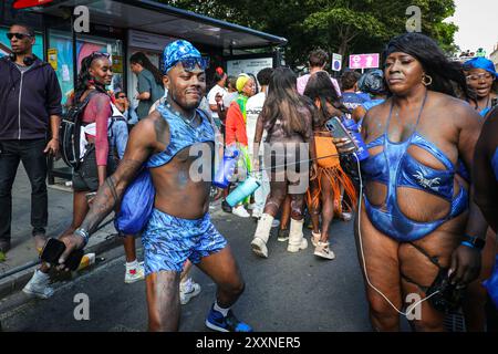 London, UK, 25th Aug 2024. Participants with the 'Blue Dutty Mas' group are covered in bright paint powders and celebrate some of the symbolisms and mas (masquerade) characters of J'Ouvert, part of the Caribbean carnival, especially in Trinidad. The usual Sunday morning J'Ouvert was cancelled, but revellers still celebrated later on. Notting Hill Carnival Sunday started with the traditional Children's Carnival today and later saw revellers celebrate the Bank Holiday Weekend participating or watching along the carnival route, at sounds systems, stalls and venues. Stock Photo