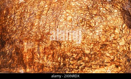 Crumpled copper foil is creating a textured and abstract metallic background Stock Photo
