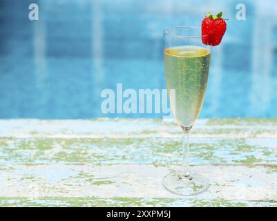 Champagne glass with strawberry on turquiose background Summer pool party Stock Photo