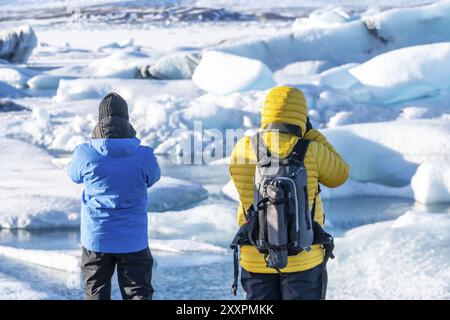 A couple of tourists looking at floating icebergs in Jokulsarlon glacier lagoon in Iceland Stock Photo