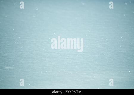 Close up of icy, frosty snow on a frozen lake during winter time with sparkling blue snowy landscape Stock Photo
