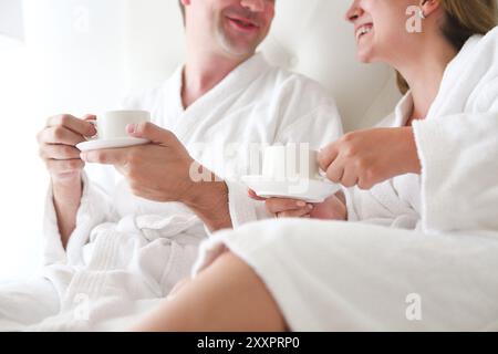 Man and woman in bathrobe drinking coffee in the bed. Morning breakfast Stock Photo